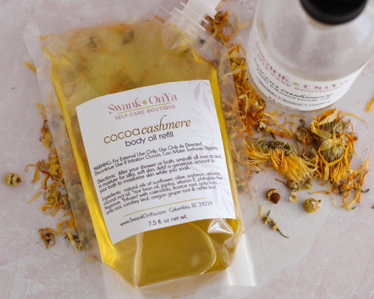 SwankOnYa cocoa cashmere body oil refill package on a light pink background with dried flowers.