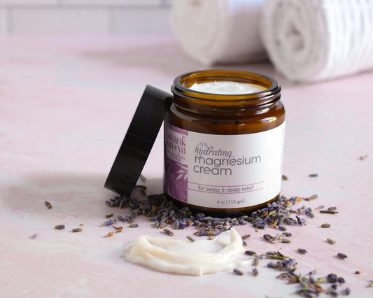 Jar of hydrating magnesium cream with lavender flowers on a pink surface