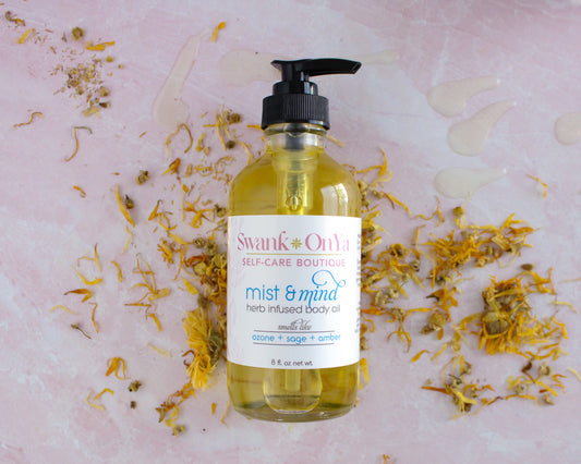 Bottle of 'Mist & Mind' herb infused body oil with a pump on a pink background with dried flowers.